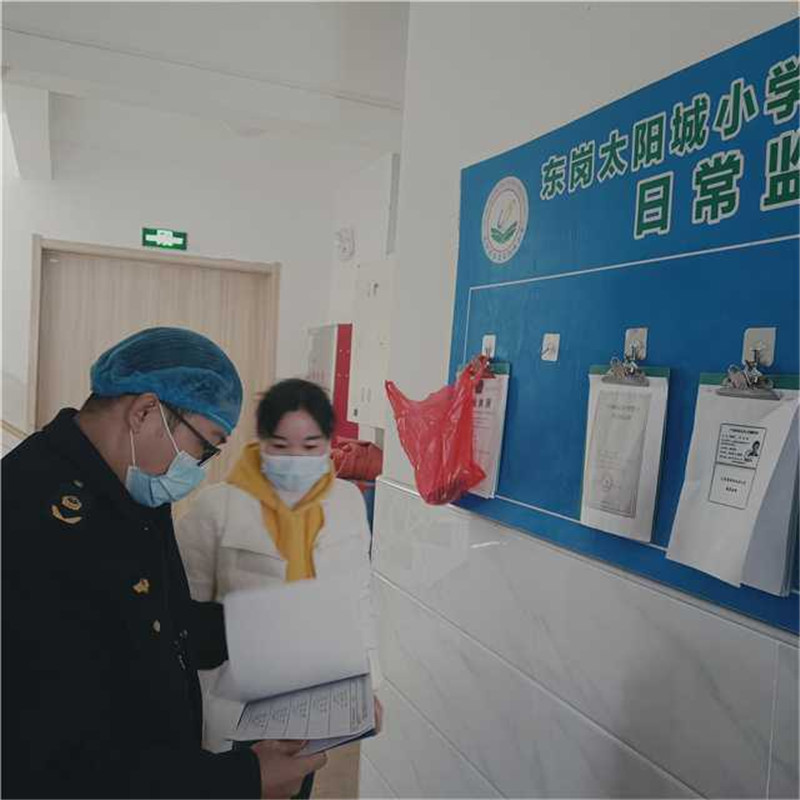 執法人員正在檢查學校食堂食品采購索證索票、進貨查驗臺賬.jpg